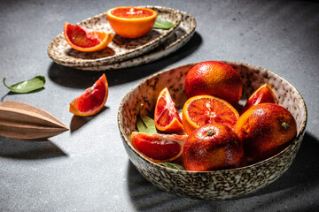 Bloody Sicilian oranges on a grey background, whole and cut sliced, halved with leaves, pattern. top view