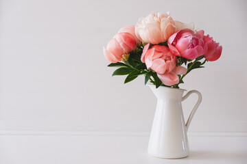 Beautiful bouquet of fresh coral peony flowers in full bloom in vase. Floral still life with blooming peonies. Negative space for text. © Iryna