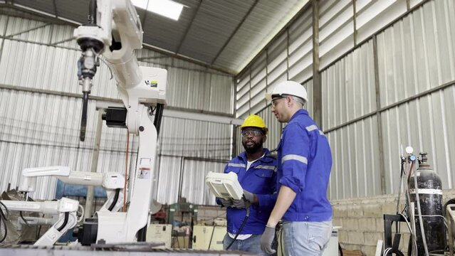 Robotic Arm engineer check on equipment in its with software of an Artificial Intelligence Computer Processor Unit.. Industrial factory employee working in metal manufacturing industry
