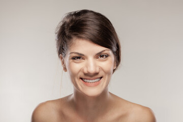 Portrait of a beautiful girl with happy face expression. Smiling lady against gray background.