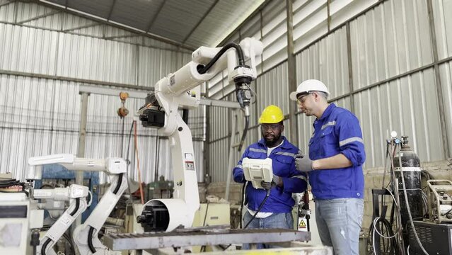 Robotic Arm engineer check on equipment in its with software of an Artificial Intelligence Computer Processor Unit.. Industrial factory employee working in metal manufacturing industry