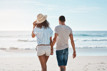 I want you by my side throughout life. Rearview shot of a young couple walking along the beach.