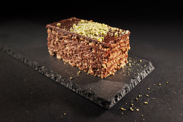 Chocolate cake with walnuts and pistachio isolated on black background. Pastry from homemade bakery