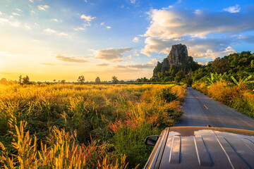 Beautiful field on the road with limestone mountain and sky at sunset, view from car roof, Noen Maprang, Phitsanulok, countryside of Thailand