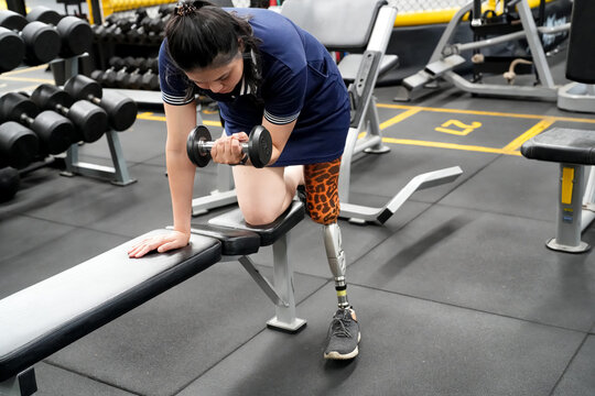 Disabled athlete with leg prosthesis training at the gym. Paralympic Sport Concept.