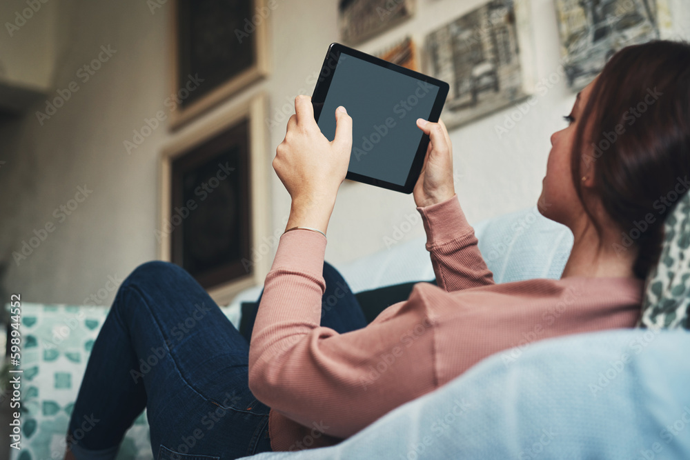 Poster The tv screen looks super tiny these days. a young woman using a digital tablet while relaxing at home.