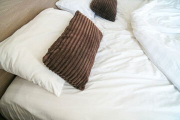 brown corduroy small backrest pillow sheets in front of white pillows and bed.