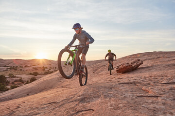 Fototapeta na wymiar Full speed ahead. Full length shot of two young male athletes mountain biking in the wilderness.