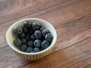blueberries in a bowl on a dark wooden table
