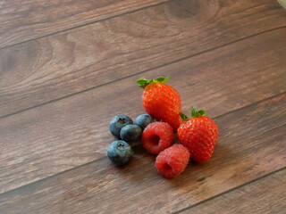 strawberries, raspberries and blueberries on wooden background close up