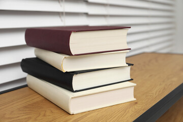 Stack of hardcover books on wooden table indoors, closeup