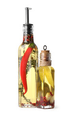 Glass bottles of cooking oil with spices and herbs on white background