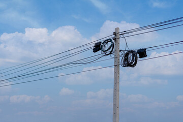 Black boxes and cable reels on poles. Internet box or splitter box with high-speed fiber optic cable hanging on a metal electric pole.