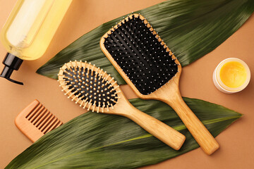 Flat lay composition with wooden hairbrushes and cosmetic products on light brown background