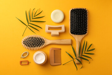 Flat lay composition with wooden brushes and different hair products on orange background