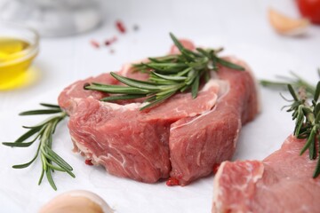 Fresh raw meat with rosemary on parchment paper, closeup