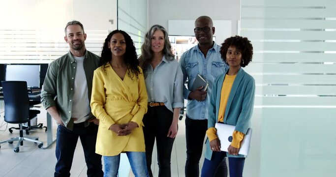 Diverse group of confident businessmen and businesswomen standing side by side together in a bright modern office