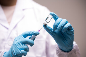 Doctor hand in blue gloves holding influenza vaccine for prevention human.Concept fight against virus covid-19 corona virus, scientist in laboratory holding a syringe with liquid vaccines for children