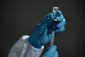 Doctor hand in blue gloves holding influenza vaccine for prevention human.Concept fight against human papilloma virus, nurse in laboratory holding a syringe with HPV vaccines for girl and woman.