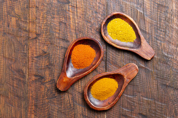 Turmeric, pepper and curry powder in container on wooden background