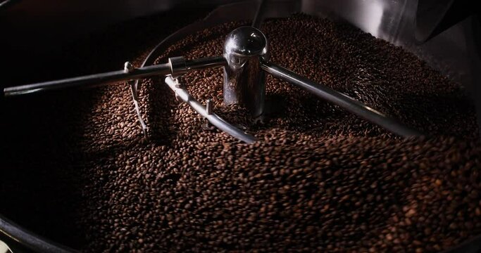 Close-up of the spinning blades of a modern coffee roaster. Coffee beans inside. Arabica coffee production concept.