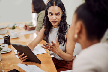 Do you get what Im saying. a young businesswoman using a digital tablet while having a discussion with a colleague in an office.