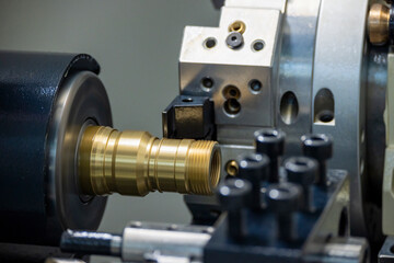 Close up scene the CNC lathe machine thread cutting at the end of brass pipe coupling parts. - obrazy, fototapety, plakaty