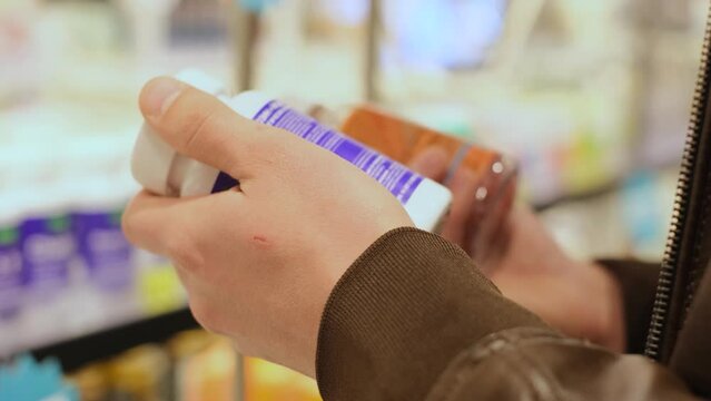 The buyer reads the composition of dietary supplements in a store