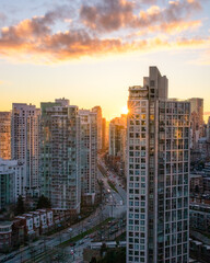 Fototapeta na wymiar Sunset over a city skyline with a road winding between buildings. Pacific Blvd and False Creek in Vancouver, Canada