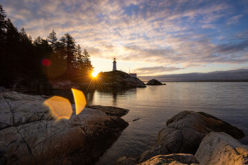 Naklejka premium Sunrise over a tall lighthouse situated on a rugged rocky coast - Point Atkinson Lighthouse Park, Vancouver 