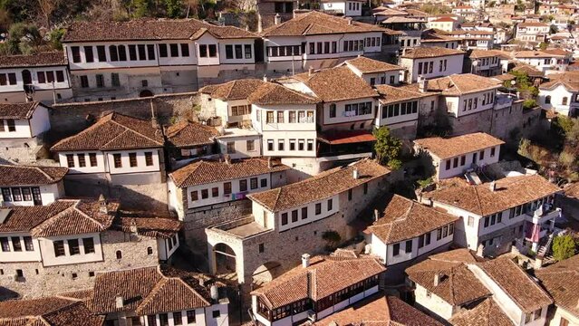 Flying over tiled roofs of houses, mosques and minarets in Berat, Albania. Magnificent Ottoman buildings in the most beautiful city of Albania - Berat. Aerial view, 4K