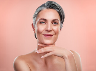 Im sure you want to know my secrets to beautiful skin. Studio portrait of a beautiful mature woman posing against a peach background.