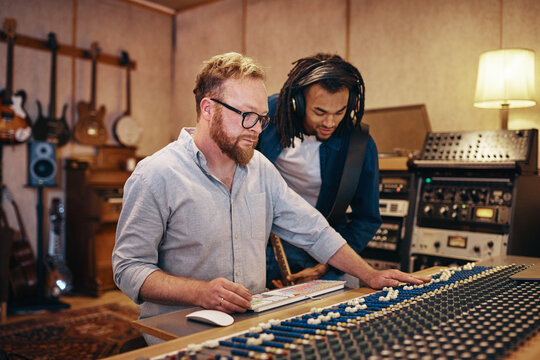 Producer and musician working on tracks in a recording studio