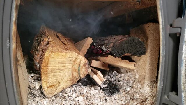 
Close up smoldering wood inside of cast iron log wood stove.
