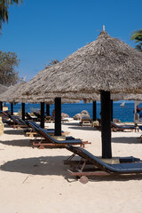 Beach huts and chaise pool lounger chairs on the beach in Zanzibar Tanzania on a sunny day