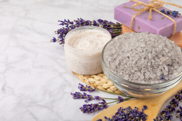 Lavender spa.Sea salt,lavender flowers,aroma candle,body cream and handmade soap.Natural herbal cosmetics with lavender flowers on marble background.Relax concept.Beauty treatments.Copy space.