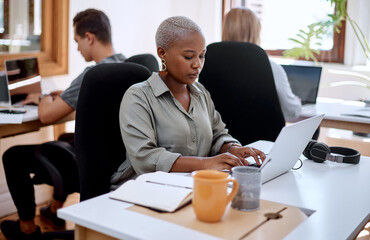 Putting some focus into it. a young businesswoman working on a laptop in an office.