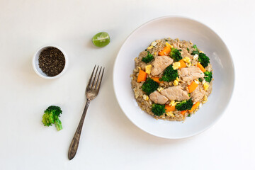 Fried rice with chicken breast has vegetable broccoli pumpkin in bowl on white wood table.