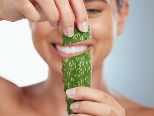 Closeup of smiling beautiful woman holding aloe vera leaf for her skincare routine. Caucasian model...