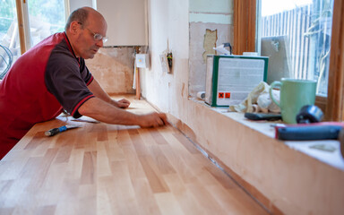 Kitchen Fitters: Wooden Worktop. A fitter applying silicon sealant to fill and make a worktop...