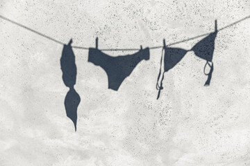 summer and silhouette concept - shadow of lingerie or swimwear hanging on rope outdoors on concrete...