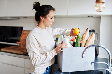 Smiling woman unpacking groceries