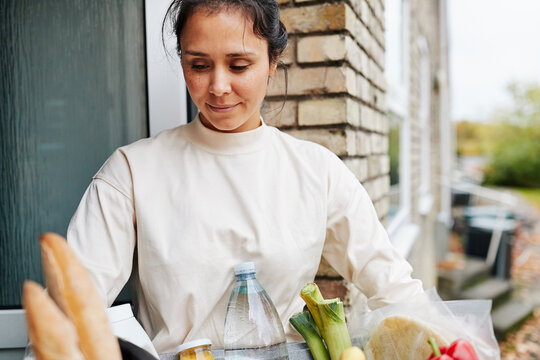 Woman holding a grocery delivery box outside