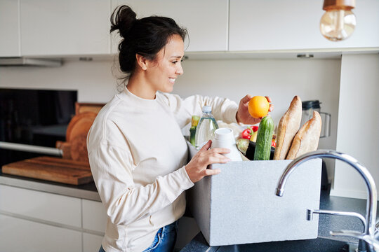Smiling woman unpacking groceries