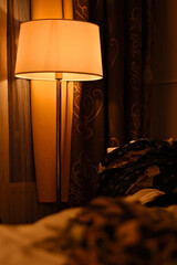 Hotel room with a romantic feeling. Beautiful lampshade giving warm yellow light. Gorgeous brown...