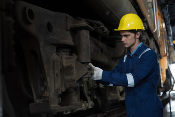 Male engineer worker maintenance locomotive engine. Technician inspecting quality parts of locomotive engine in locomotive garage. Male railway engineer repair engine in garage
