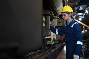 Male engineer worker maintenance locomotive engine. Technician inspecting quality parts of locomotive engine in locomotive garage. Male railway engineer repair engine in garage