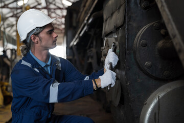 Male engineer worker maintenance locomotive engine. Technician inspecting quality parts of locomotive engine in locomotive garage. Male railway engineer repair engine in garage