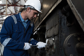 Male engineer worker maintenance locomotive engine. Technician inspecting quality parts of locomotive engine in locomotive garage. Male railway engineer repair engine in garage