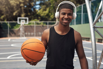 Fototapeta premium Ive been shooting hoops since I was a kid. Portrait of a sporty young man listening to music while playing basketball on a sports court.